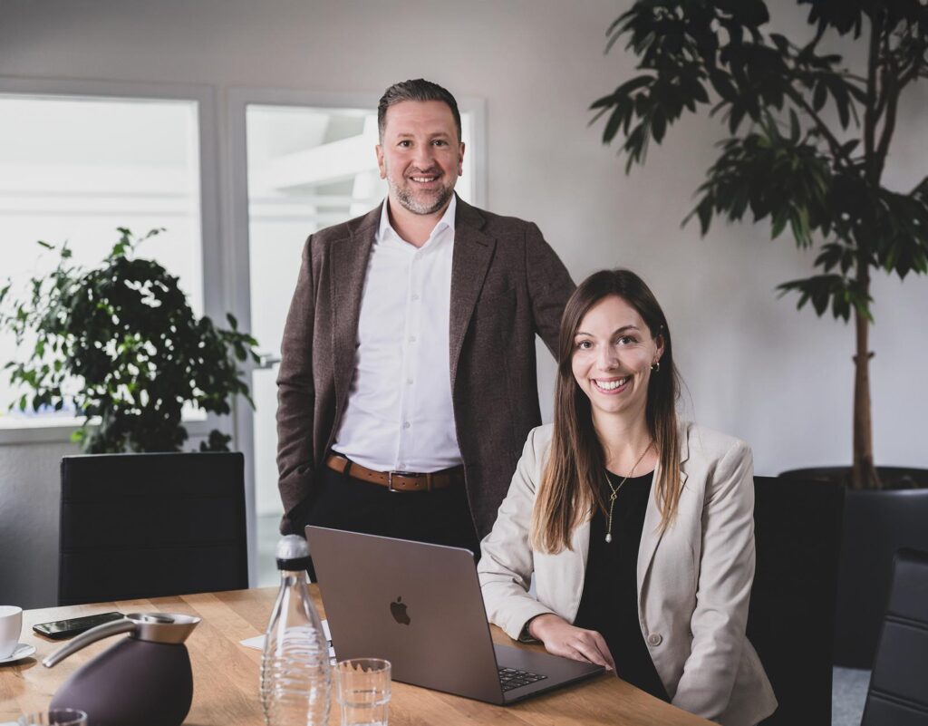 Christopher Lemm steht neben Louisa Gilbert am Schreibtisch